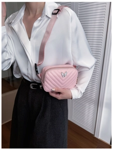 Close-up of pink mini crossbody bag with V-shaped quilting and butterfly metal buckle