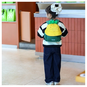 Detail view of cartoon pineapple kid's backpack with 3D leaves and vibrant yellow finish