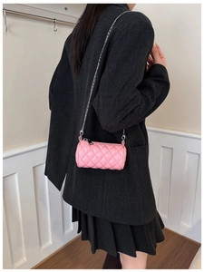 Pink quilted cylinder bag for children with silver chain strap worn by a young model