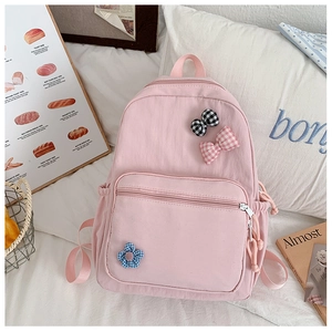 Pink school backpack with cute floral and bow patches on a soft aesthetic bed setting