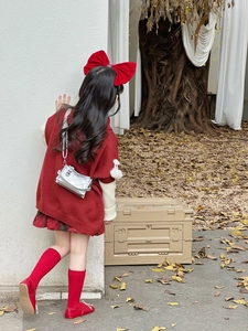 Detail of a red knitted sweater and silver quilted crossbody bag for a stylish girl outfit