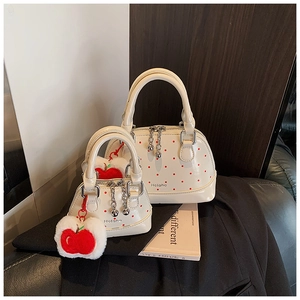 Detailed view of white polka dot shell bags with apple charms in two sizes