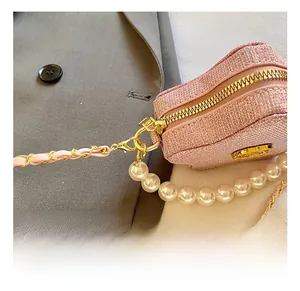 Close-up of pink glitter star bag with large pearls and gold metal chain strap detail