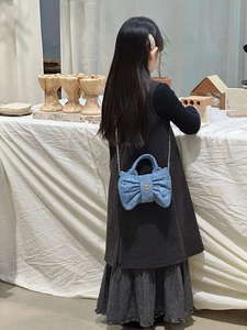 Detail of light blue denim bow bag with quilted pattern and gold chain strap for kids