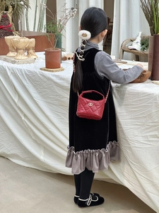Vue de dos d'un enfant portant un sac à bandoulière en cuir rouge matelassé avec chaîne
