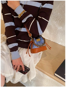 Détail du mini sac seau en patchwork de denim bleu avec bandoulière chaîne dorée