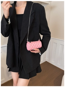 Close-up of pink quilted cylinder bag featuring a silver metal chain strap and sleek zipper