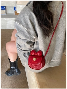 Détail du mini sac bandoulière rouge en cuir verni pour enfant avec nœud et ours en métal