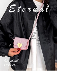 Détail du mini sac à paillettes roses avec boucle cœur dorée porté sur cuir noir