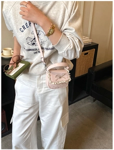 Close-up of pink girls' mini crossbody bag with lace trim, bow, and hollow heart patterns