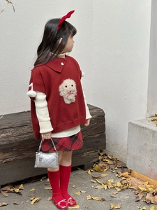 Mädchen mit gesteppter silberner Handtasche zu roter Strickweste und Karo-Rock