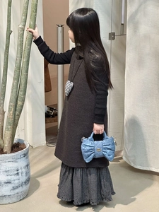 Detail of blue denim bow handbag with gold buckle held by girl in elegant dress