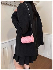 Pink quilted cylinder mini bag with silver chain strap worn by a child model