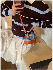 Détail du mini sac seau en jean avec motifs à carreaux bleus et chaîne dorée