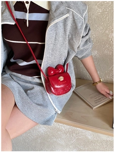 Détail du sac rouge avec nœud, pendentif ours en peluche et pois sur la bandoulière