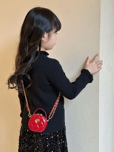 Detail einer roten gesteppten Lackleder-Rundtasche für Mädchen mit goldener Kette