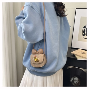 Detail of a brown mini crossbody bag for girls featuring a 3D bow and cartoon bear patch