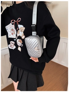 Detail of silver quilted waist bag featuring a white butterfly emblem and adjustable strap