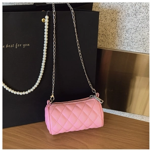 Pink quilted cylinder bag with silver chain strap shown in a stylish gift setting