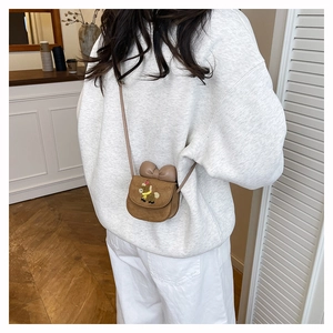 Rear view of a girl wearing a brown suede crossbody bag with bow and cartoon embroidery