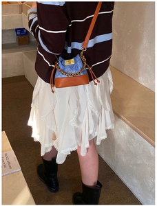 Détail d'un mini sac seau en jean avec bordure en cuir marron et chaîne dorée