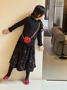 Detail einer roten gesteppten Minitasche mit Goldkette am Outfit eines Kindermodells
