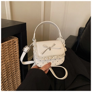 Detail of white mini bag featuring lace trim, bow decoration, and heart-shaped polka dots