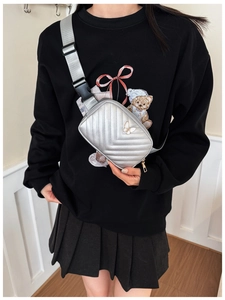 Close-up of silver quilted crossbody bag with a white butterfly logo on a child model