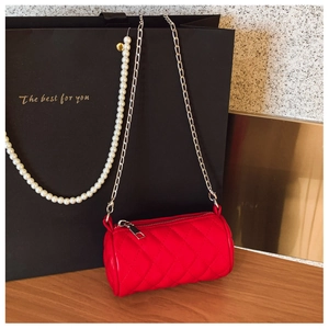 Detailed close-up of a red quilted cylinder shoulder bag with a silver chain strap