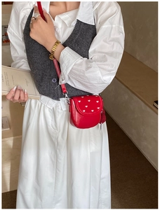 Détail du sac bandoulière rouge à motif cœurs avec boucle argentée en décor lifestyle