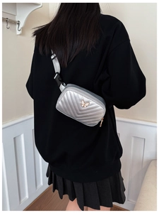 Close-up of silver quilted waist bag featuring a decorative butterfly metal buckle