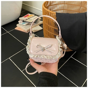 Detail of pink mini bag with white lace edges, bow and metal heart pendant