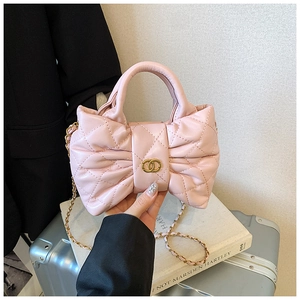 Detail view of pink bow-shaped handbag with quilted pattern and gold metal chain strap