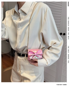 Close-up of pink laser-textured mini bag with bow detail and gold chain strap