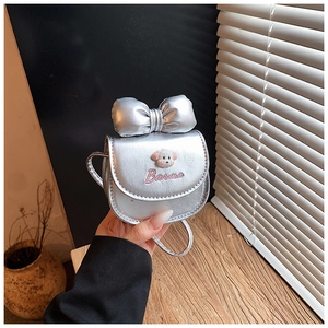 Détail d'un sac argenté pour enfant avec grand nœud et broderie de chien en peluche
