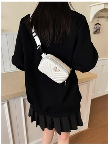 Close-up of white quilted mini crossbody bag featuring a golden butterfly logo and strap