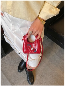 Dettaglio mini borsa a tracolla rossa trapuntata con patch pony su camicia gialla