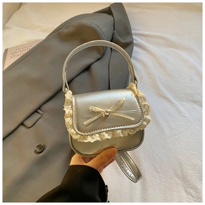 Detail of silver girls handbag featuring white lace edges and heart pendant