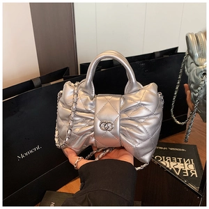 Detail of silver bow handbag with quilted texture and metal chain strap for girls