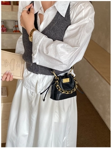 Détail d'un mini sac seau noir matelassé avec chaîne dorée et fermeture par cordon