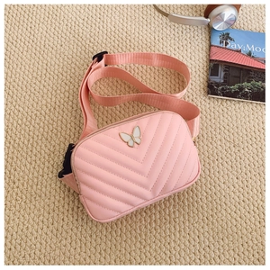 Close-up of pink quilted crossbody bag with white butterfly metal charm and nylon strap
