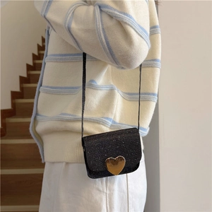 Mini sac bandoulière noir pailleté pour fille avec fermoir cœur porté sur un gilet rayé