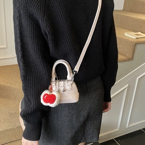 Sac coquille rose à pois pour enfants avec breloque cerise, porté par un enfant