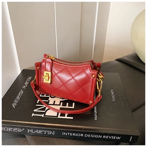 Nahaufnahme der roten Steppnähte und des goldenen Drehverschlusses an der Mini-Handtasche