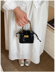Détail d'un mini sac seau matelassé noir avec poignée en chaîne dorée et fermoir tournant