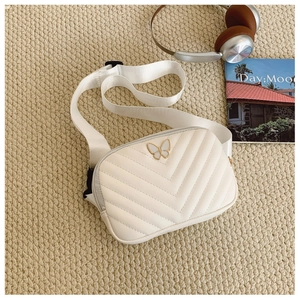Detail of cream quilted crossbody bag with golden butterfly ornament and strap