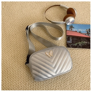 Close-up of silver quilted crossbody bag with white butterfly and adjustable strap