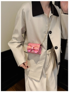 Detail of pink metallic bow crossbody bag with gold chain strap on model for size reference