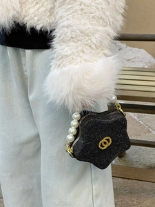 Detail of a sparkling black star-shaped kids handbag with pearl handle and logo
