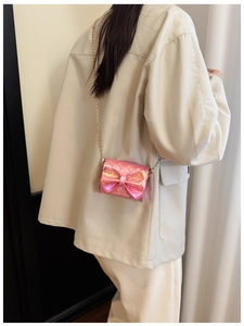 Detail of a pink holographic mini crossbody bag with golden chain on a child model